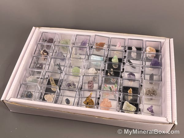 Bulk003 actual mixed mineral specimen box with about 35 different mini natural specimens, including likely fluorite, garnet, stibnite, quartz, aquamarine, tourmaline and grape agate.