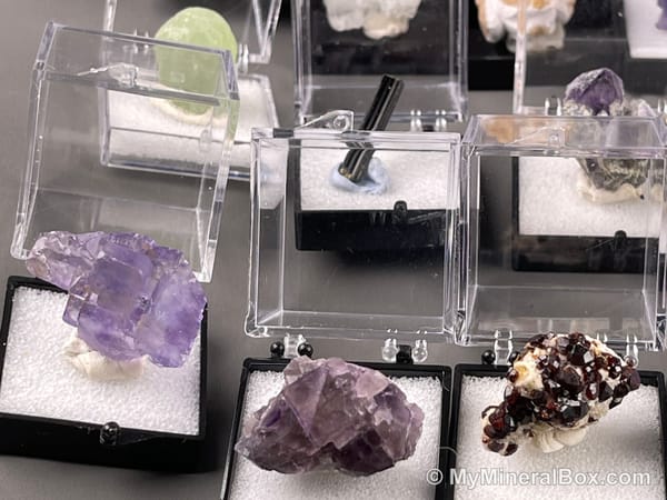 Bulk003 actual mixed mineral specimen box with about 35 different mini natural specimens, including likely fluorite, garnet, stibnite, quartz, aquamarine, tourmaline and grape agate.