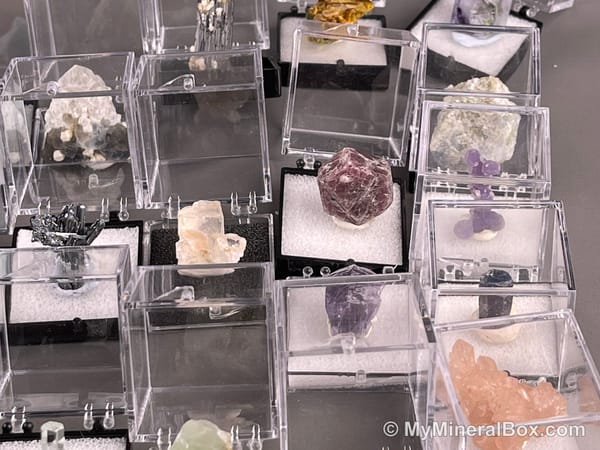 Bulk003 actual mixed mineral specimen box with about 35 different mini natural specimens, including likely fluorite, garnet, stibnite, quartz, aquamarine, tourmaline and grape agate.