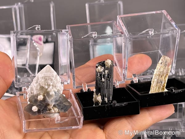 Bulk003 actual mixed mineral specimen box with about 35 different mini natural specimens, including likely fluorite, garnet, stibnite, quartz, aquamarine, tourmaline and grape agate.