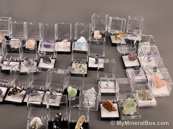 Bulk003 actual mixed mineral specimen box with about 35 different mini natural specimens, including likely fluorite, garnet, stibnite, quartz, aquamarine, tourmaline and grape agate.