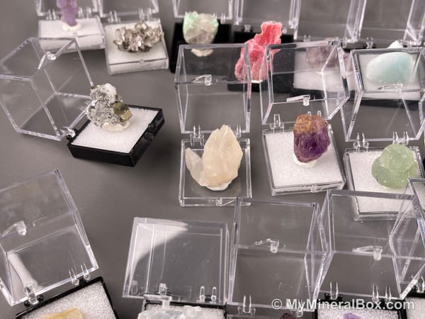 Bulk004 actual mixed mineral specimen box with about 35 different mini natural specimens, including likely fluorite, black tourmaline, quartz, stibnite, grape agate and green prehnite-type material.