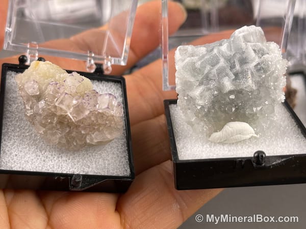 Bulk004 actual mixed mineral specimen box with about 35 different mini natural specimens, including likely fluorite, black tourmaline, quartz, stibnite, grape agate and green prehnite-type material.