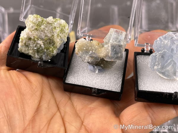 Bulk004 actual mixed mineral specimen box with about 35 different mini natural specimens, including likely fluorite, black tourmaline, quartz, stibnite, grape agate and green prehnite-type material.
