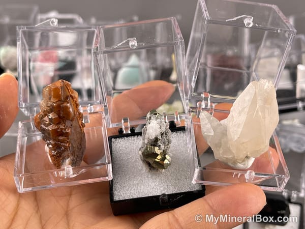 Bulk004 actual mixed mineral specimen box with about 35 different mini natural specimens, including likely fluorite, black tourmaline, quartz, stibnite, grape agate and green prehnite-type material.
