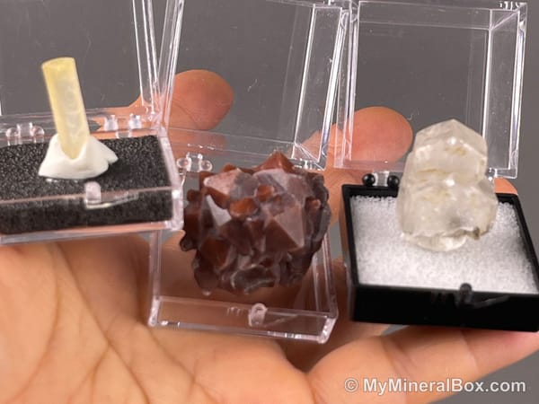 Bulk004 actual mixed mineral specimen box with about 35 different mini natural specimens, including likely fluorite, black tourmaline, quartz, stibnite, grape agate and green prehnite-type material.