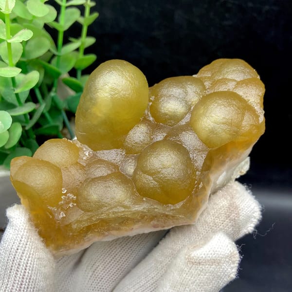 Angled front view of the tall oval fluorite nodule above smaller golden domes