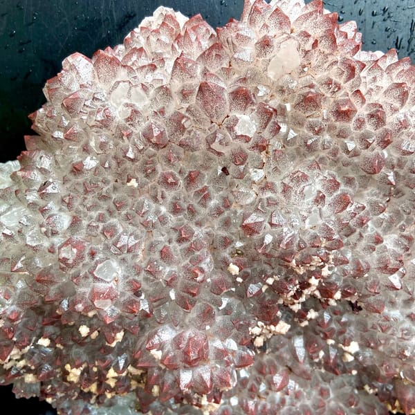 Fan of red-skinned quartz points with dolomite on stand from Jiangxi, China, close-up of the crystal faces