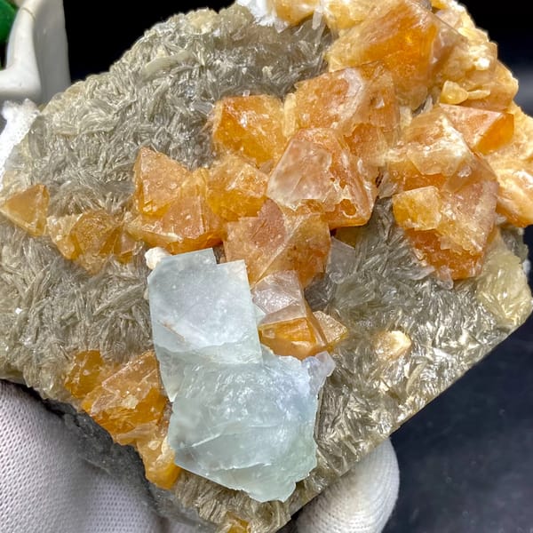 Orange scheelite crystals with pale blue fluorite on mica from Xuebaoding, Sichuan, China, close-up of terminations