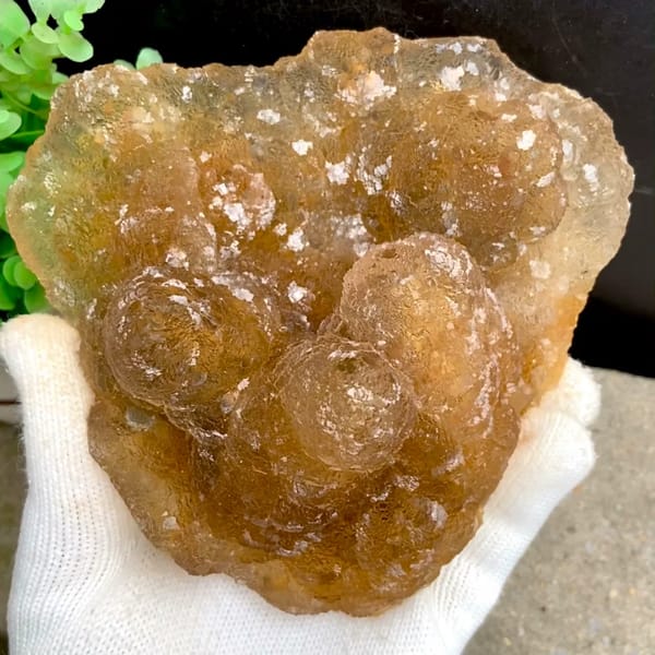 Amber pineapple fluorite of stacked translucent columns from Henan, China, held in gloved hand