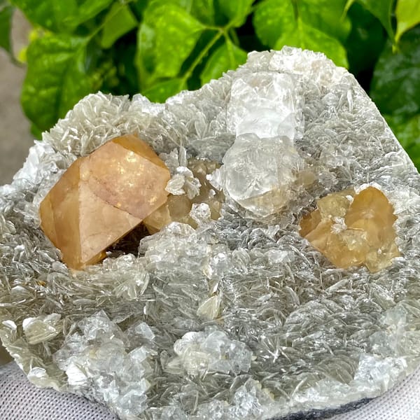 Orange scheelite and frosted fluorite on silvery mica from Xuebaoding, Sichuan, China, close-up of terminations