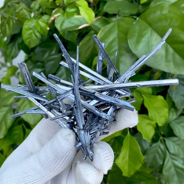 Floater spray of steel-grey stibnite needles from Jiangxi, China, held in gloved hand