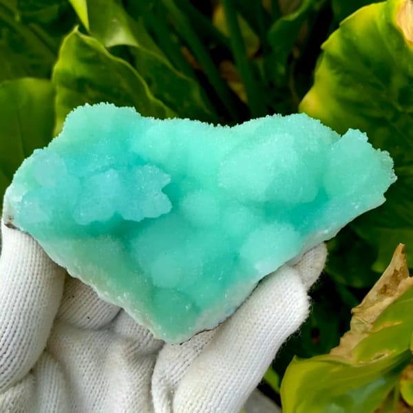 Mound of mint-green acicular aragonite from Sichuan, China, held in gloved hand