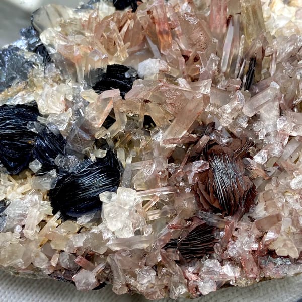 Plate of black specular hematite with pink-skinned quartz from Guangdong, China, side view