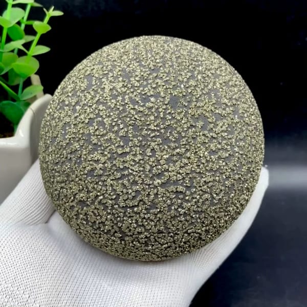Large iron concretion sphere dusted with pyrite from Yunnan, China, held in gloved hand