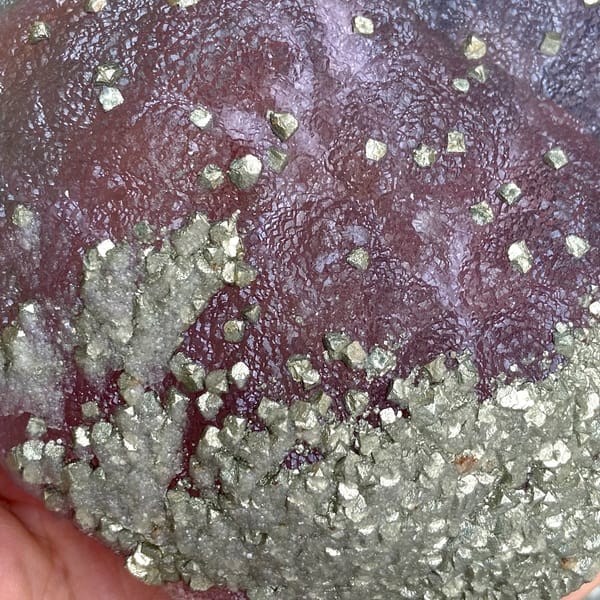 Pink-purple botryoidal fluorite dome speckled with pyrite from Jiangxi, China, close-up of the crystal faces