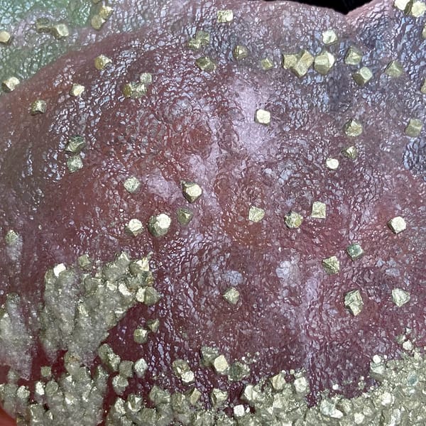 Pink-purple botryoidal fluorite dome speckled with pyrite from Jiangxi, China, detail of the matrix contact