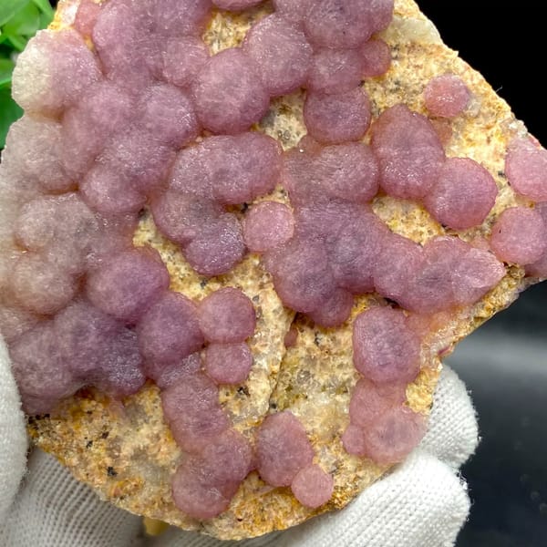 Dusty pink botryoidal fluorite balls on tan plate from Henan, China, side view