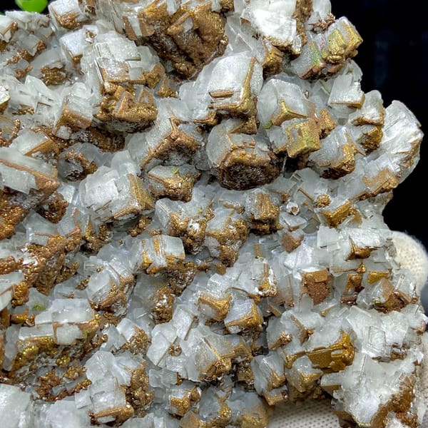 Plate of pale pyramid calcite coated in rusty iridescent pyrite from Hunan, China, close-up of the crystal faces