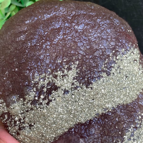 Plum-purple botryoidal fluorite ball dusted with pyrite from Jiangxi, China, detail of the matrix contact