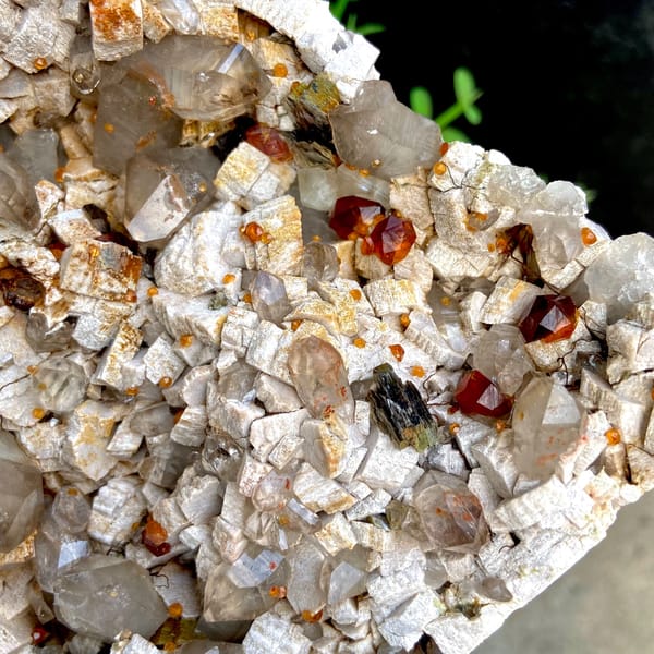 Wine-red garnets scattered over pale quartz plate from Fujian, China, top view