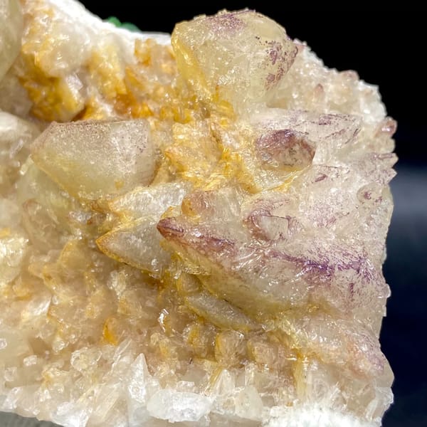 Pale calcite rhombs with yttrian fluorite on golden quartz from Guizhou, China, detail of the matrix contact