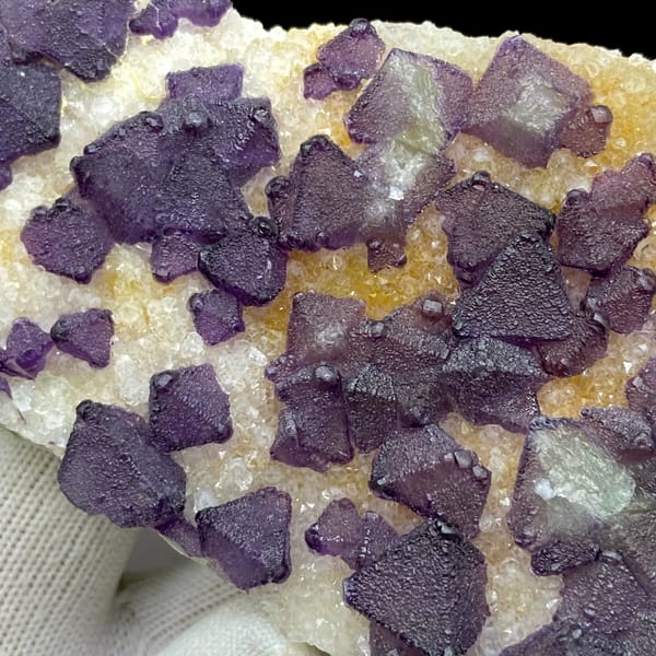 Plate of purple fluorite octahedra on white quartz from Zhejiang, China, close-up of the crystal faces