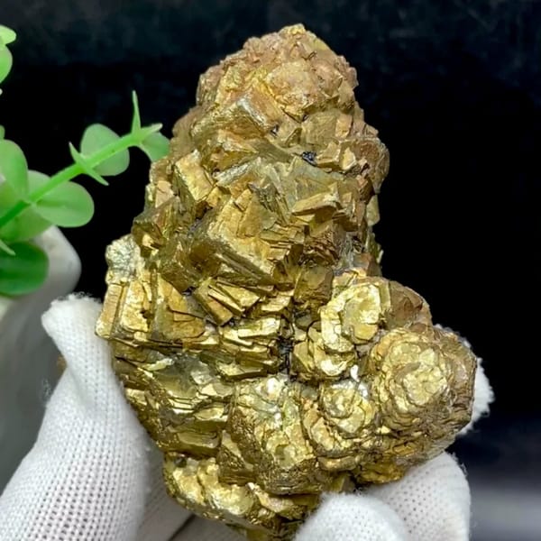 Stack of stepped brassy pyrite crystals from Yunnan, China, held in gloved hand