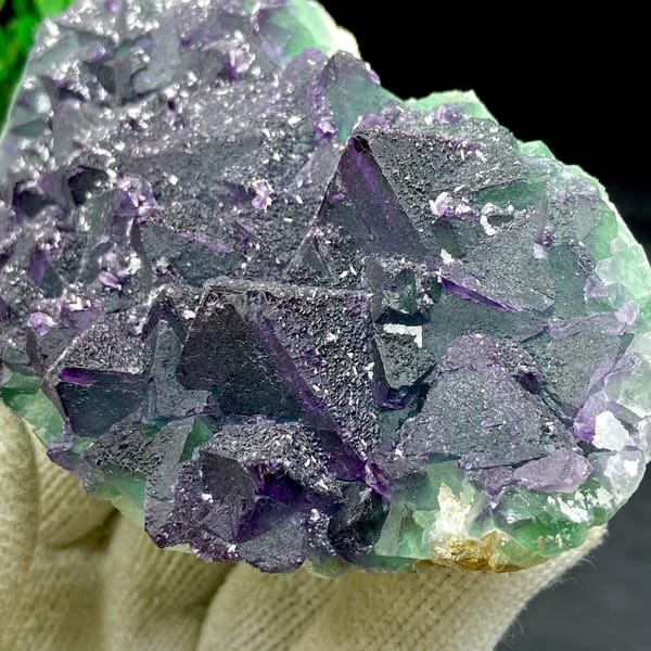 Dark green fluorite octahedra with purple edges and sparkling coating from Zhejiang, China, close-up of the crystal faces