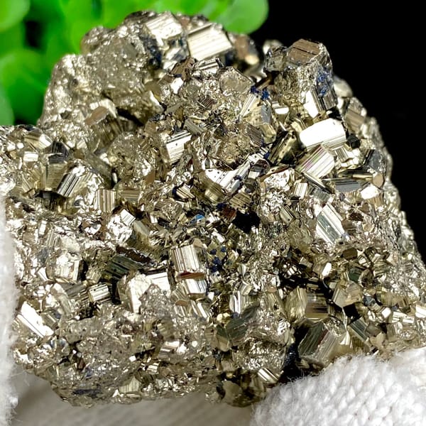 Rounded cluster of bright pyrite dodecahedra from Peru, close-up of the crystal faces