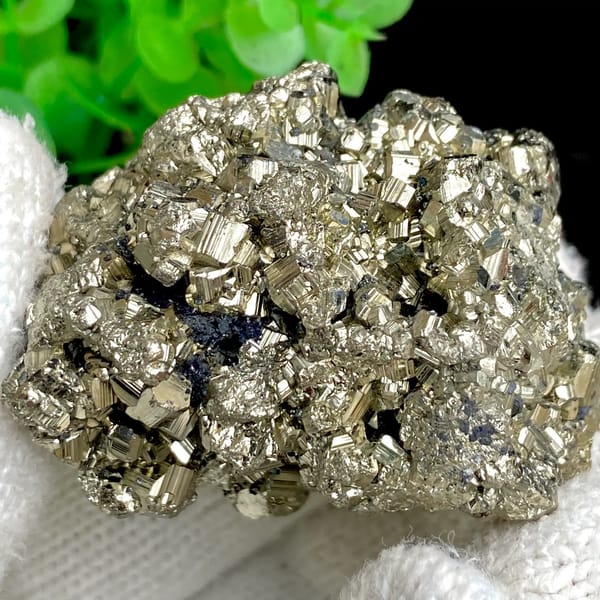 Rounded cluster of bright pyrite dodecahedra from Peru, detail of the matrix contact