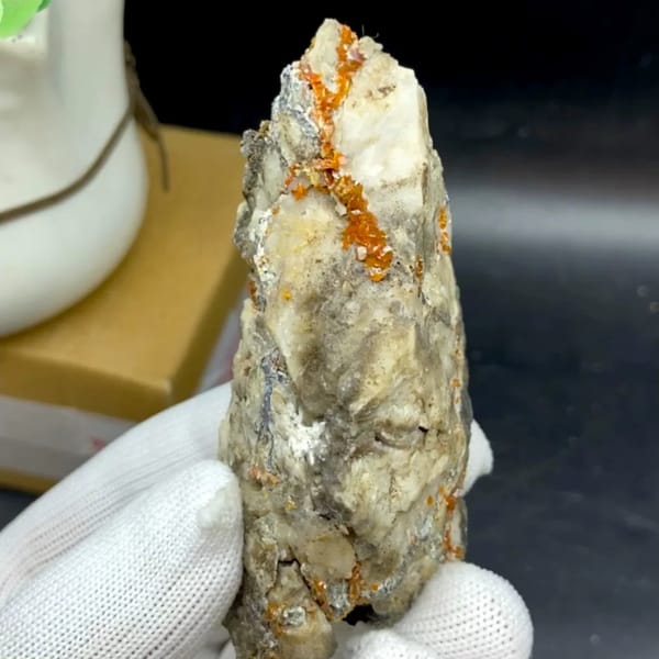 Tall white matrix wedge with orange-red wulfenite from Sichuan, China, held in gloved hand