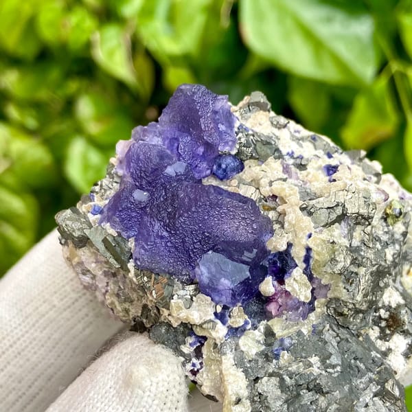 Vivid purple fluorite octahedron on grey arsenopyrite from Inner Mongolia, China, detail of the matrix contact
