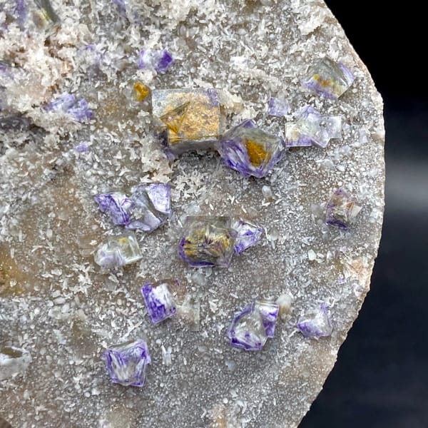 Small purple-edged garden fluorite cubes on grey plate from Hebei, China, second angle