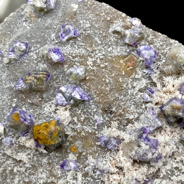 Small purple-edged garden fluorite cubes on grey plate from Hebei, China, top view