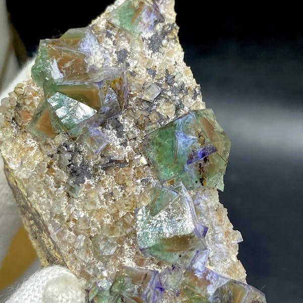Green fluorite cubes with purple edges on grey matrix from Hebei, China, detail of the matrix contact