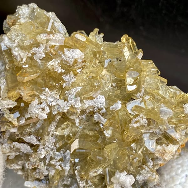 Dense cluster of golden transparent baryte blades from Yunnan, China, detail of the matrix contact