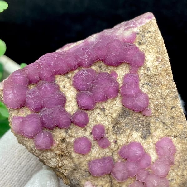 Purple-pink strawberry fluorite balls on sandy triangle from Henan, China, close-up of the crystal faces