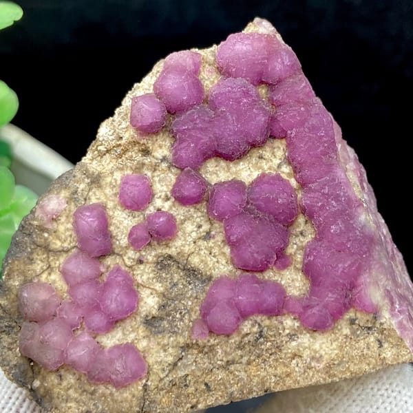 Purple-pink strawberry fluorite balls on sandy triangle from Henan, China, detail of the matrix contact