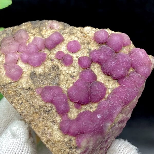 Purple-pink strawberry fluorite balls on sandy triangle from Henan, China, side view