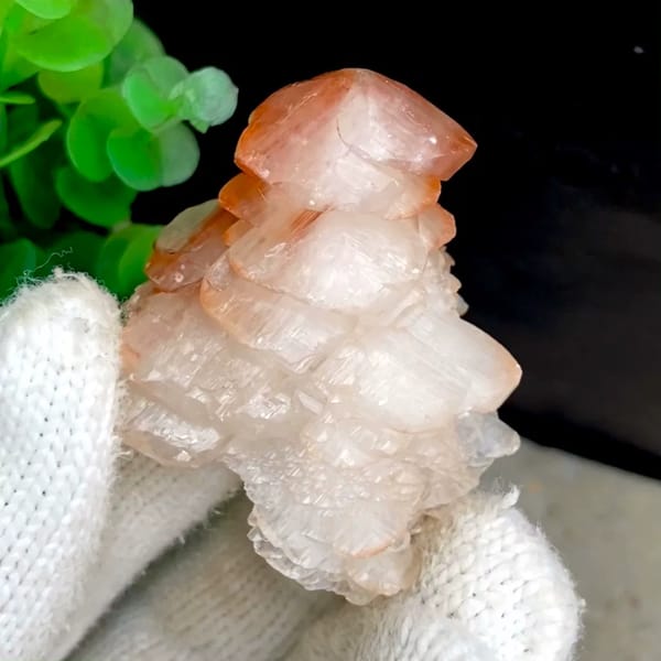 Pagoda-shaped calcite with red-capped top from Hubei, China, held in gloved hand