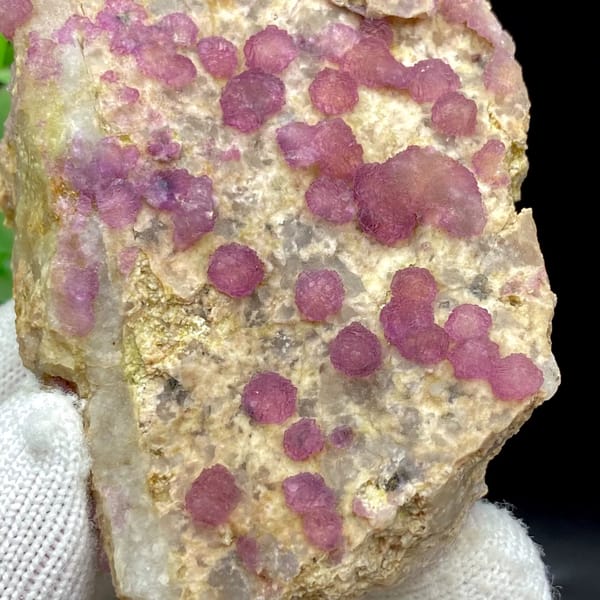 Raspberry strawberry-fluorite balls on tall tan plate from Henan, China, detail of the matrix contact