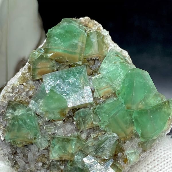 Transparent green fluorite cubes on sparkling quartz from Hebei, China, detail of the matrix contact