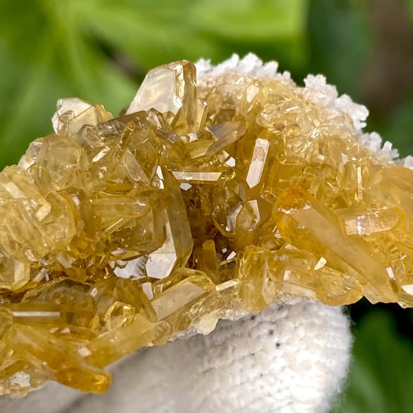 Golden transparent baryte blades on white base from Yunnan, China, close-up of the crystal faces