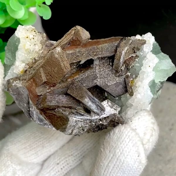 Brown bladed calcite with green fluorite and quartz from Fujian, China, held in gloved hand