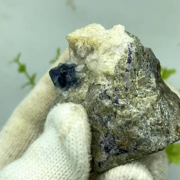 Dark two-tone phantom fluorite cube on grey-green matrix from Inner Mongolia, China, held in gloved hand