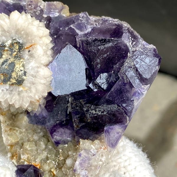 Deep purple fluorite cubes above white bladed calcite from Fujian, China, close-up of the crystal faces