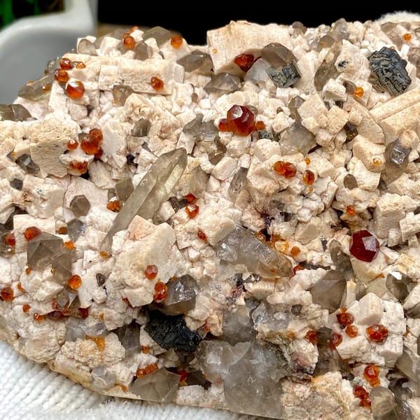 Bar of feldspar dotted with Fanta-orange spessartine and smoky quartz from Yunxiao, Fujian, China, second angle