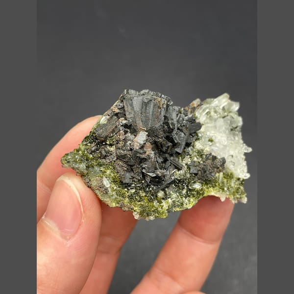 Dark bladed crystals with green epidote and quartz from Zhaotong — detail view