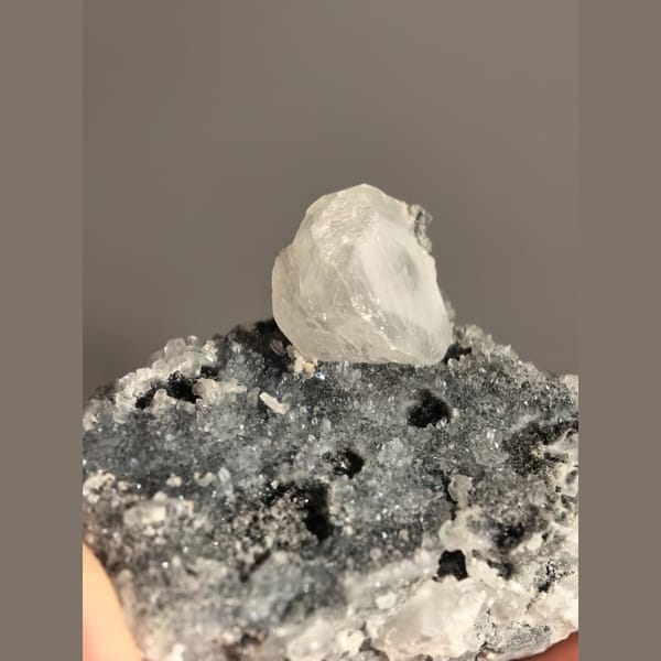 Single quartz crystal on matrix with small biscuit calcite crystals — complete view